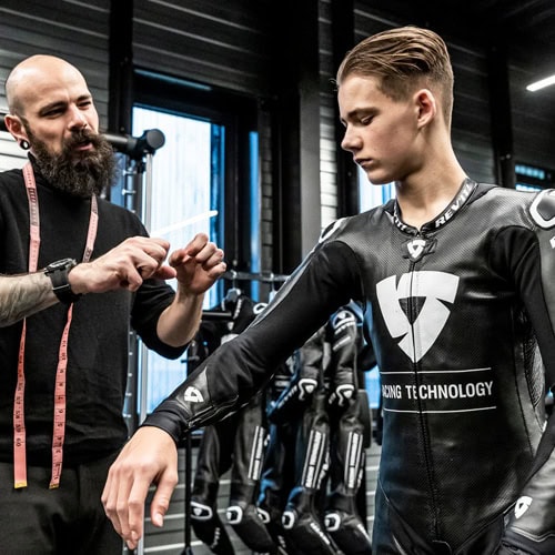 Tecnico specializzato verifica la vestibilità di una tuta moto su misura durante la prova statica con il pilota