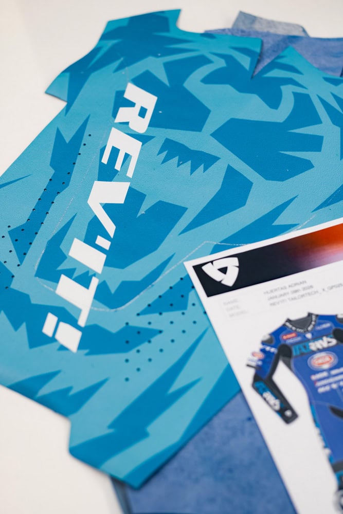 Detajl motorističnega kombinezona REV’IT! po meri s personalizirano grafiko dirkača